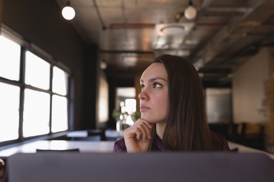 Thoughtful businesswoman sitting at desk in office
