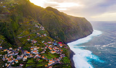 Aerial tropical island cliff view with huge white waves by the shore