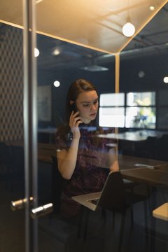 Businesswoman talking on mobile phone at desk