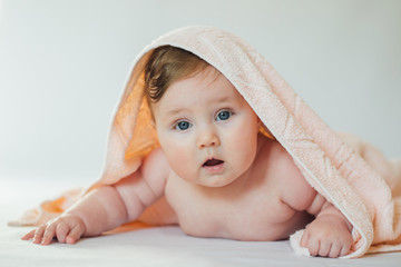 Cute baby covered with a bath towel lying on tummy