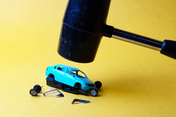 broken down blue car model toy over which hung hammer black