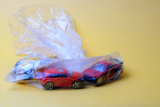 three toy cars in a plastic transparent bag on a yellow background