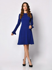 Young beautiful woman posing in new dark  blue fashion winter dress on a white