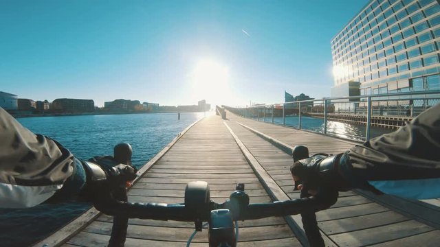 Point of view of athlete riding bicycle next to harbour as sun sets