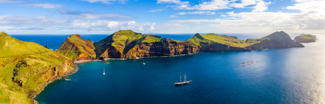 Aerial tropical island view in the middle of the ocean with rocky cliffs and green fields