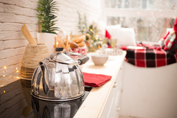Interior light kitchen with red decor and Christmas decorations. Preparing holiday dinner at home on the kitchen concept. Decorated new Year fir. Selective focus