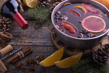 Freshly prepared aromatic muled wine with fragrant species in a pan on a wooden dark background....