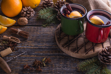 Obraz na płótnie Canvas Christmas traditional hot drink in two mugs with species and orange on a wooden background. Place for text.