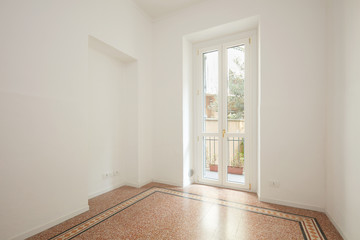 Empty, white living room with large window in a renovated apartment