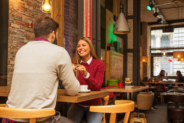 Man giving a present to his girlfriend in cafe and she is surprise