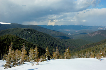 Winter mountain landscape with snow covered road forest hills snow and blue sky with clouds