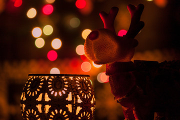 Christmas reindeer figure with candles and bokeh lights in background.