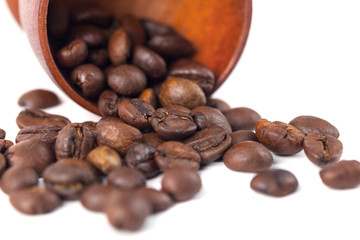 Roasted coffee beans in wooden cup on a white background