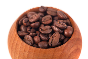 Roasted coffee beans in wooden cup on a white background