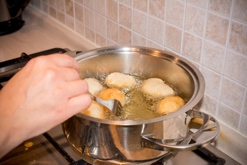Woman's hands that Adjusting the Dough Friying in a Pot during the Preparation of an Italian Christmas Traditional Dish called Pettole
