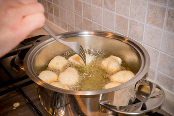Woman's hands that Adjusting the Dough Friying in a Pot during the Preparation of an Italian Christmas Traditional Dish called Pettole