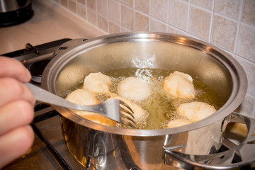 Woman's hands that Adjusting the Dough Friying in a Pot during the Preparation of an Italian Christmas Traditional Dish called Pettole