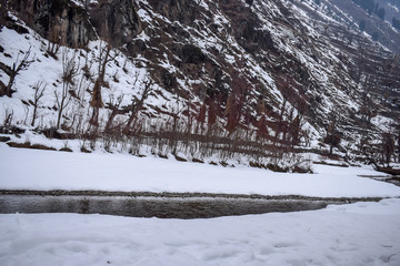 Stunning snow landscape with snow covered mountains and beautiful river in Betaab Valley, Pahalgam. Snow covered forest & forest lodges during Christmas/New Year holidays in Kashmir, India.