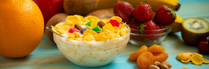 Tasty cornflakes with milk and fruits  in glass bowl