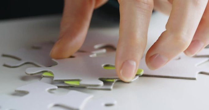 Female hands looking for a specific jigsaw puzzle piece. Chroma key compositing possible.