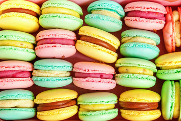 Sweet almond colorful pink, blue, yellow, green macaron or macaroon dessert cake background. French sweet cookie. Minimal food bakery concept. Flat lay, top view, copy space