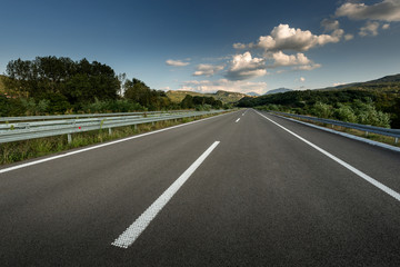 Asphalt highway road through the countryside to the mountains