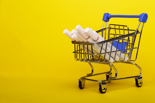 Smoking concept. Cigarettes in shopping cart, shopping trolley on yellow background