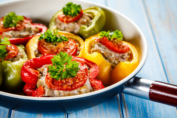 Stuffed peppers in frying pan on wooden table