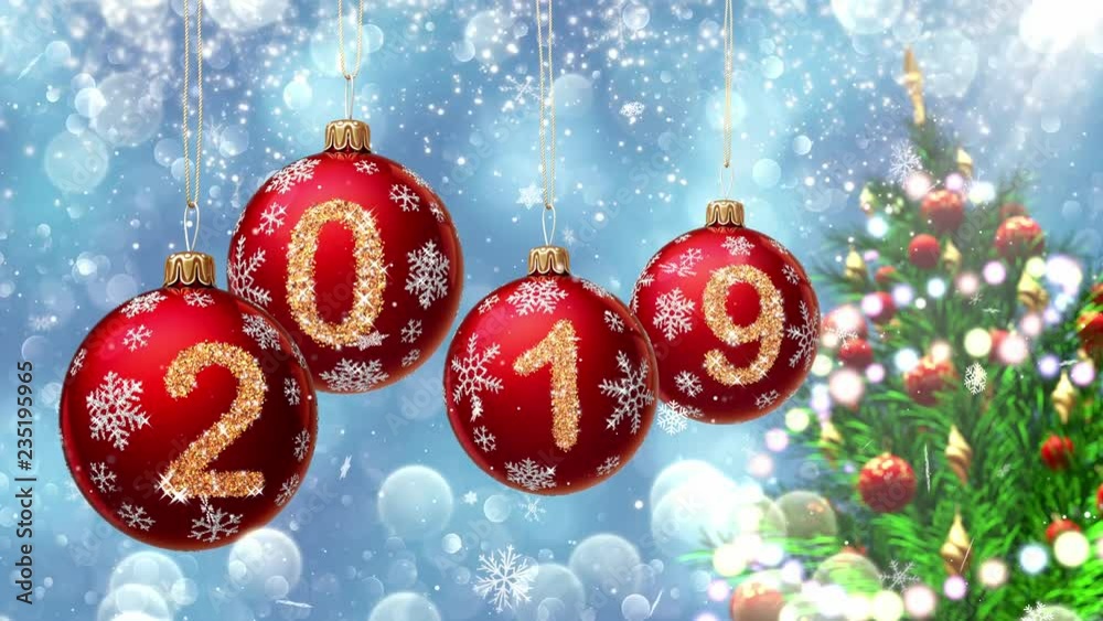 Wall mural red balls with numbers 2019 hanging on the background of a blue bokeh and a rotating christmas tree 