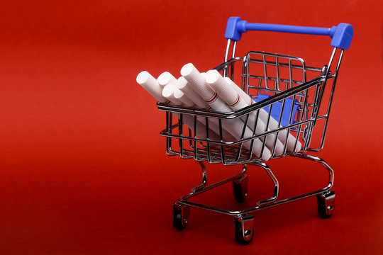 Smoking concept. Cigarettes in shopping cart, shopping trolley on red background