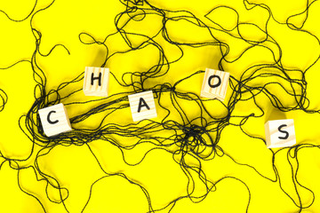 Word Chaos made of wooden cubes on the yellow background.