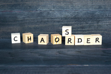 Words  Chaos and Order made of wooden cubes on the dark background.