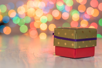 Christmas gifts or present boxes. Colorful lights, globes and decorations in the background, on rustic wooden surface. Christmas stocking with the 