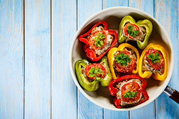 Stuffed peppers in frying pan on wooden table