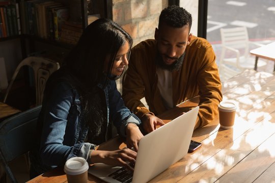 Couple using laptop in cafe