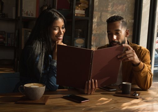 Couple Looking At Menu In Cafe