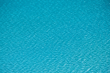 Amazing textured background of calm azure clean water surface. Sunshine in mountain lake close up. Beautiful ripples on shiny water in sunny day. Wonderful relax texture.
