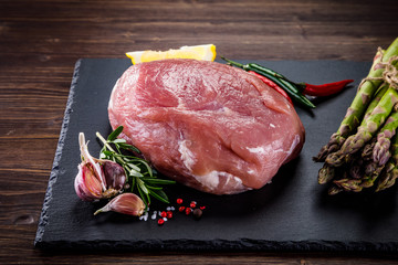 Fresh raw pork with vegetables on cutting board on wooden background