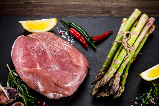Fresh raw pork with vegetables on cutting board on wooden background