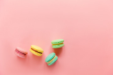 Sweet almond colorful pink blue yellow green macaron or macaroon dessert cake isolated on trendy pink pastel background. French sweet cookie. Minimal food bakery concept. Flat lay top view copy space