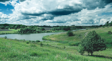 Obraz premium Cloudy summer landscape with small river.