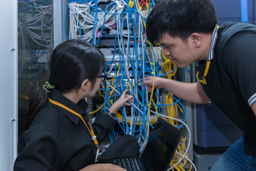 Two asian engineers working in the server room,Check the connection problems of computer networks,Thailand people