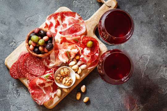 Top view of meat plate, cold smoked pork, jamon, prosciutto, salami served with wine, nuts and olives from above