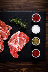 Raw beefsteaks on black stone on wooden background