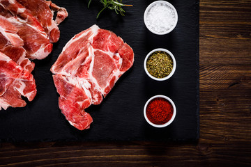 Raw beefsteaks on black stone on wooden background