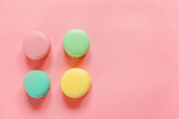 Sweet almond colorful pink blue yellow green macaron or macaroon dessert cake isolated on trendy pink pastel background. French sweet cookie. Minimal food bakery concept. Flat lay top view copy space