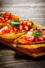 Bruschettas on cutting board on wooden background