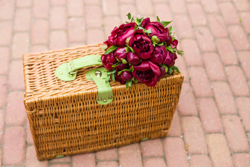 Fototapeta na wymiar Wedding bouquet of burgundy peonies lies on a wicker basket.
