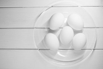White chicken eggs on a light wooden table. Black and white