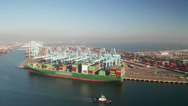 Aerial view of global trade, large container ship unloading cargo containers with cranes in the harbor.